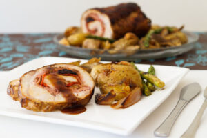 Lomo de cerdo relleno al horno con patatas, cebollitas, setas y espárragos